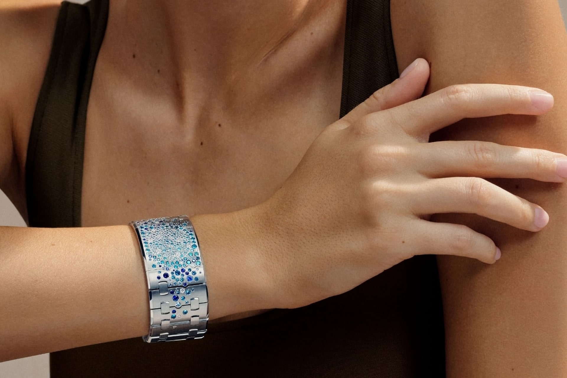 Eine Manschette mit blauen Saphiren und weissen Diamanten, die von hellem bis tiefem Blau verlaufen, am Handgelenk getragen