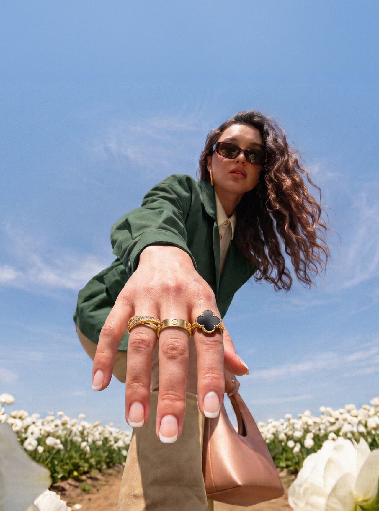 Frau mit Van Cleef & Arpels- und Cartier-Ringen in einem Blumenfeld